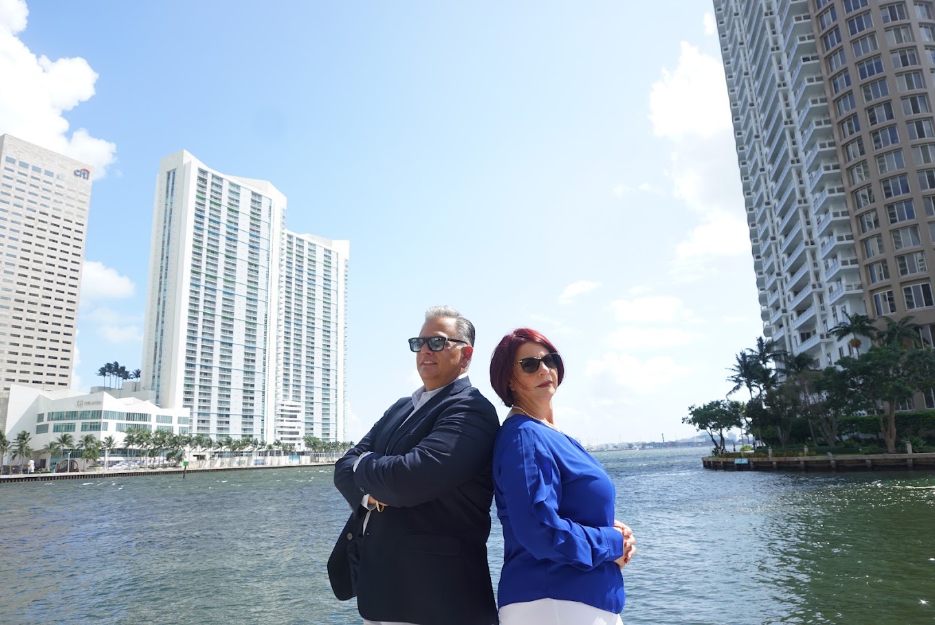 Dos personas con ropa de oficina, de espaldas una a la otra junto a una vía de agua y con edificios de la ciudad detrás, durante una sesión fotográfica corporativa de Safeguard and Associates.